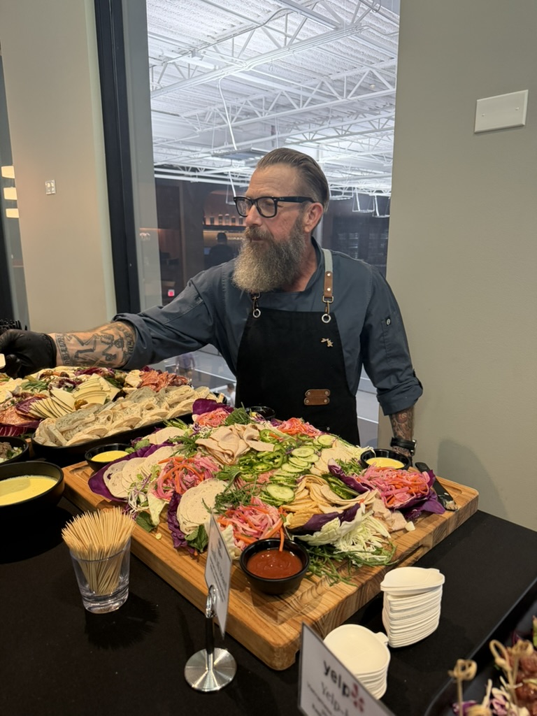 Chef Ron Matty plating a large charcuterie spread at a catered event
