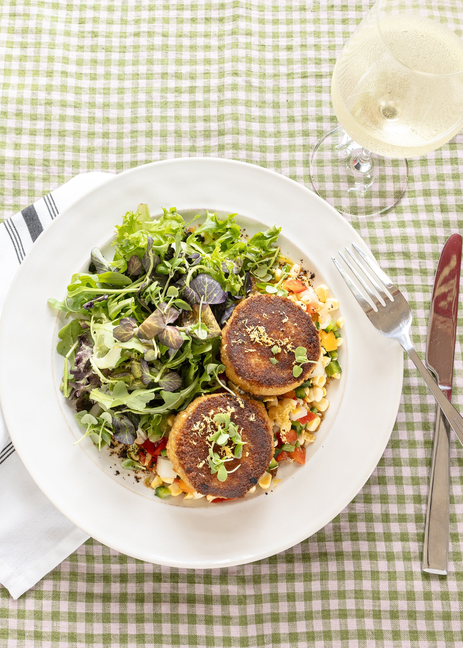 Two crab cakes over summer corn relish with field greens
