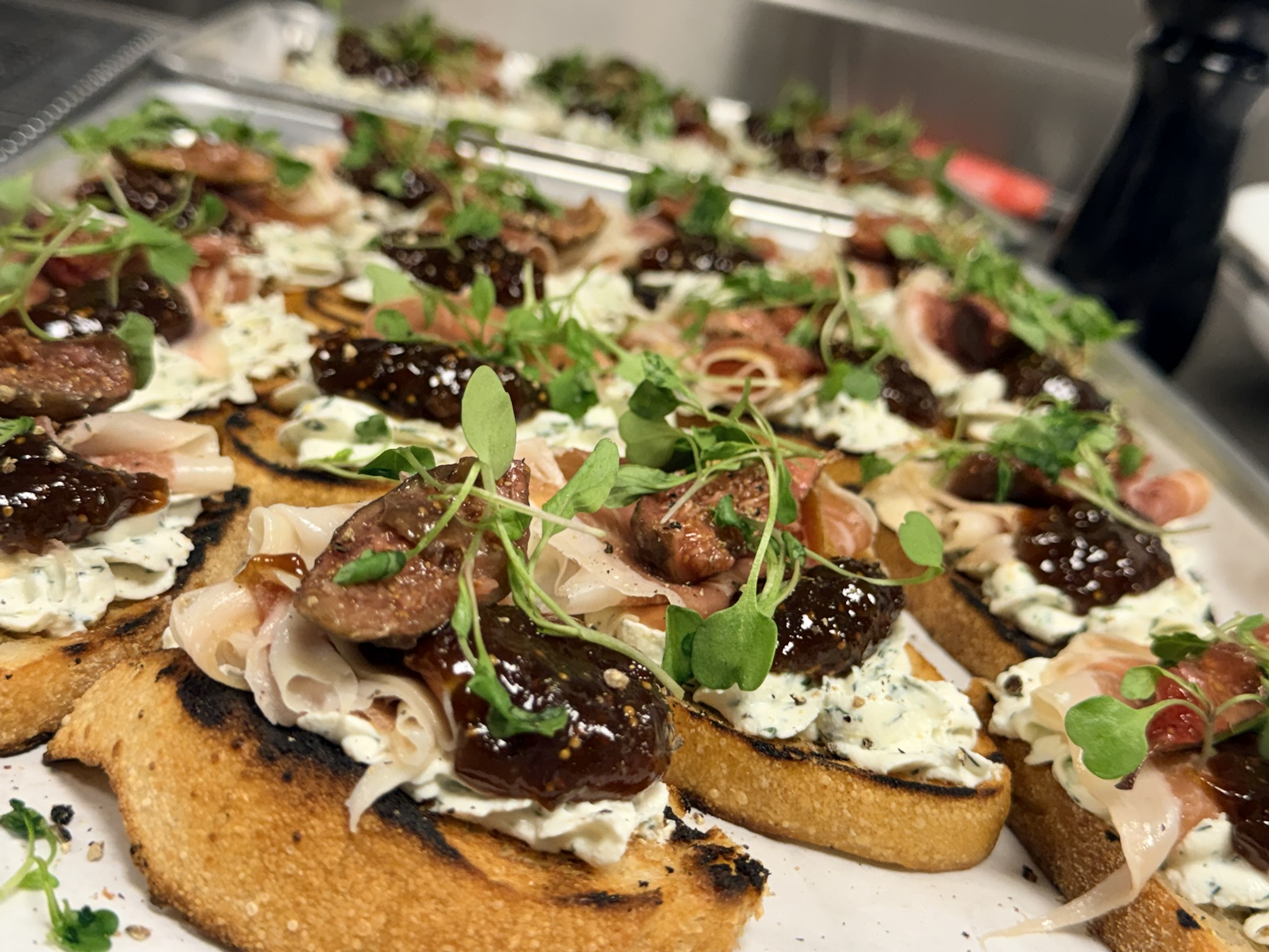 Tray of grilled bread with prosciutto, fig jam and herbed ricotta