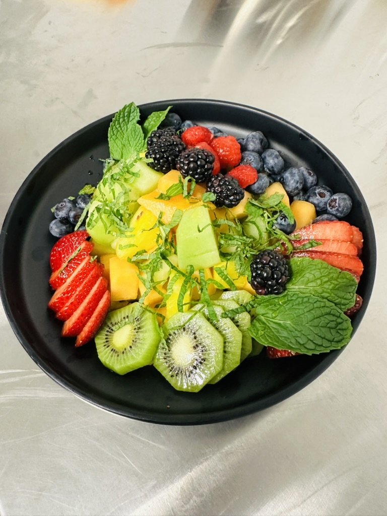 Fresh fruit bowl with berries, kiwi, melon and mint