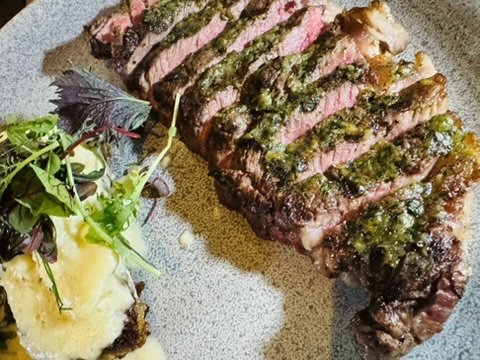 Sliced ribeye with chimichurri over potato puree and shaved salad