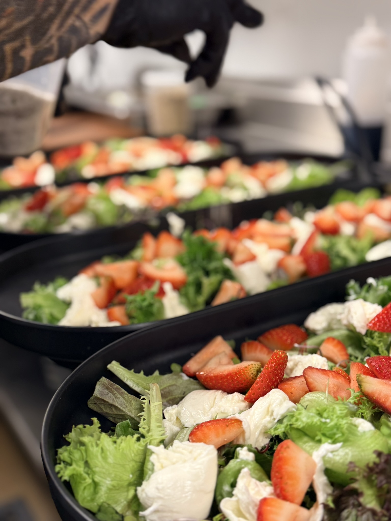 Trays of strawberry burrata salad prepped for a large event